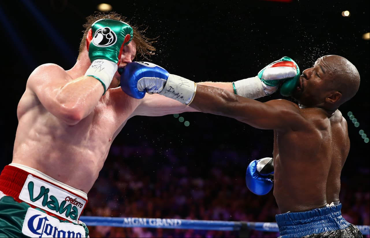 LAS VEGAS, NV - SEPTEMBER 14: (L-R) Floyd Mayweather Jr. and Canelo Alvarez exchange punches during their WBC/WBA 154-pound title fight at the MGM Grand Garden Arena on September 14, 2013 in Las Vegas, Nevada. (Photo by Al Bello/Getty Images)